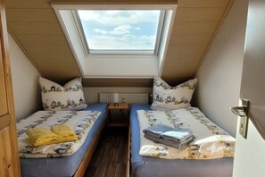 A small, cozy room with two beds, a skylight, and a radiator. - No. 8 in the Kiebitz House (Borkum)