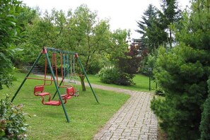 Ein Park mit einer Schaukel, einem gepflasterten Weg und umgebender Bepflanzung.