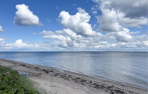 Un paisaje costero con cielo despejado, mar tranquilo y costa rocosa.