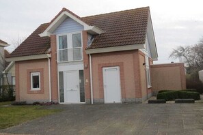 Ein zweistöckiges Haus mit einem Ziegeldach, einer Haustür und einem kleinen Vorgarten.