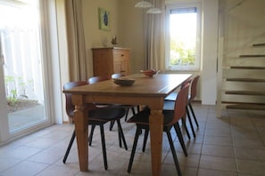 Ein Essbereich mit Holztisch, Stühlen, einem Schrank und einem Fenster mit Vorhängen.