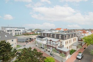 Ein Stadtplatz mit Gebäuden, einer Fußgängerzone und einem parkenden Auto.