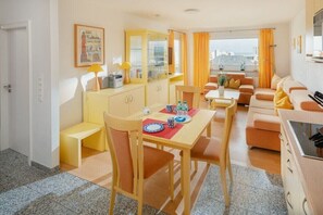 Ein kleines Hotelzimmer mit Essbereich, einer Sitzecke, einer Küchenzeile und Blick auf die Stadt.