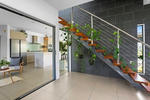Eine moderne Küche mit integrierter Kochinsel, einer Treppe mit Holzdielen und Metallgeländern sowie Topfpflanzen.