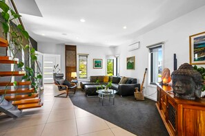 Ein modernes Wohnzimmer mit Treppe, Ledersofa und Buddha-Statue.