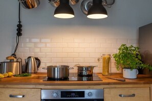 A kitchen with a stove, pots, a coffee maker, and a potted plant. - Holiday home in Ahlbeck with swimming pool (Ahlbeck)