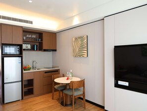 Cocina compacta con microondas, refrigerador y comedor con dos sillas y una mesa.