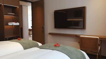Ein Hotelzimmer mit zwei Betten, einem Schreibtisch und einem an der Wand befestigten Fernseher.