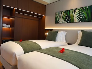 Habitación de hotel con dos camas, un cuadro grande y un armario de madera con estantes iluminados.