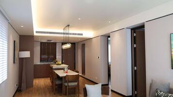 A modern living room with a dining area, wooden flooring, and a ceiling with recessed lighting.