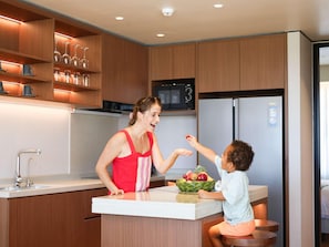 Una cocina moderna con armarios de madera, un refrigerador de acero inoxidable y un microondas.