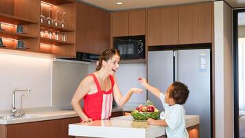 A modern kitchen with wooden cabinets, a stainless steel refrigerator, and a microwave.
