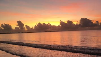 Ein Sonnenuntergang über ruhigem Wasser mit einer entfernten Küstenlinie.
