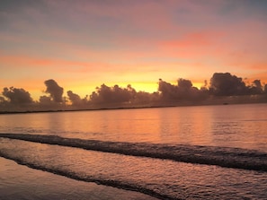 Un atardecer sobre una superficie de agua tranquila con una costa lejana.
