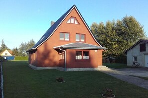 Ein eingeschossiges Haus mit Satteldach, einer kleinen Veranda und einem gepflegten Rasen.