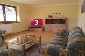 Ein Wohnzimmer mit einer Couch, einem Couchtisch, einem Fernseher und einem Schrank.
