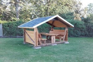 Ein hölzernes Pavillon mit geneigtem Dach und Bänken.