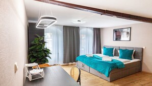 A modern bedroom with a bed, bedside table, chair, and a large window with curtains. - Apartment "Harmonie Oasis" with Wi-Fi and Air Conditioning (Alsleben)