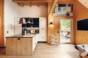 Eine moderne Küche mit Holzschränken, einer zentralen Kochinsel und einem Essbereich mit Sitzgelegenheiten im Freien.