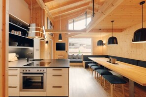Eine moderne Küche mit Holzbalken, einer zentralen Kochinsel und einer Sitzecke mit Bänken.
