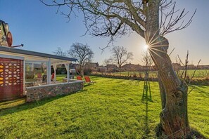 Ein Haus mit einer Terrasse, einer Steinmauer und einem Rasen.