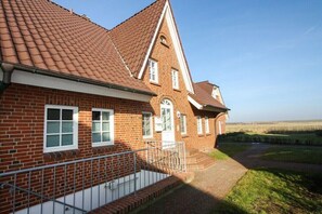 Ein Backsteinhaus mit rotem Ziegeldach, einem verschlossenen Eingang und einem Weg zu einer Rasenfläche.