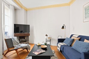 Ein Wohnzimmer mit Fernseher, Sofa, Couchtisch und Sessel.