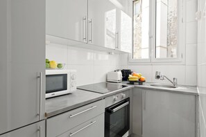 Eine moderne Küche mit weißen Schränken, einer Mikrowelle, einem Toaster, einer Spüle und einem Fenster.