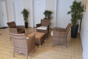 Ein Zimmer mit Korbmöbeln, Fliesenboden und Blumentöpfen.