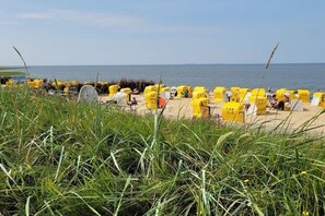 Ein Strand mit Reihen aus gelben Liegestühlen und Sonnenschirmen, einige mit sichtbaren Nummern.