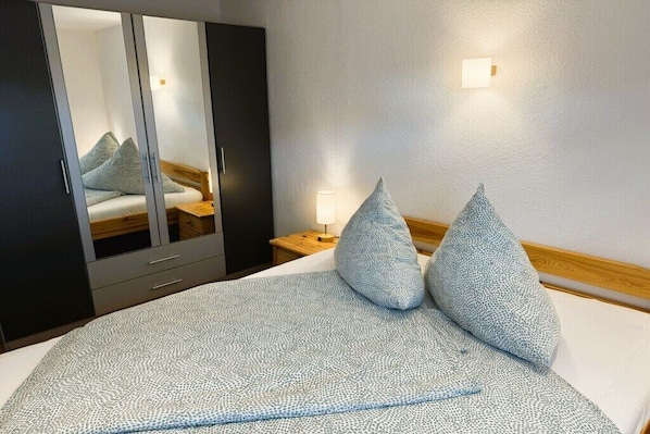A hotel room with a bed, a wardrobe, a nightstand with a lamp, and a mirror. - with boat/ house Haveleck (Ketzin\/Havel)