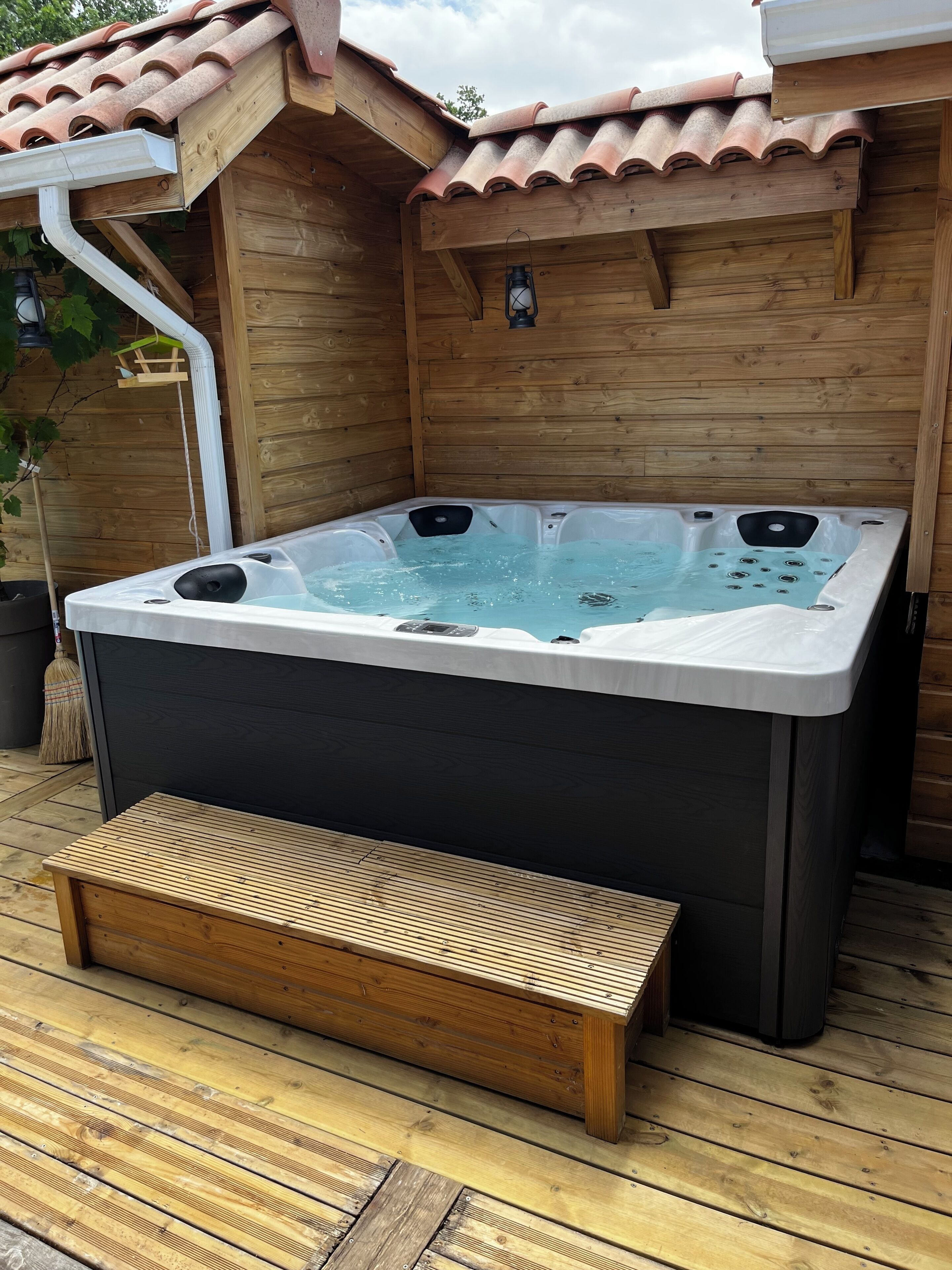 Un bain à remous avec une terrasse en bois et un mur en bois.