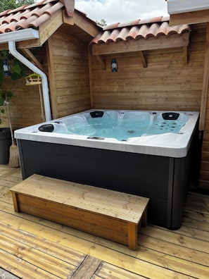 Un jacuzzi con cubierta de madera y pared de madera.