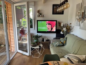 A living room with a TV, a sofa, a coffee table, and a sliding glass door leading to a balcony.