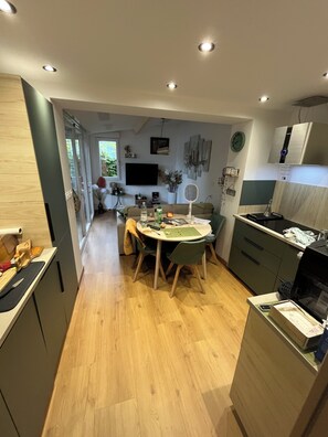 A modern kitchen with a dining area, wooden flooring, and a large window.