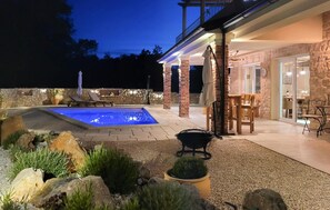 A pool with a stone patio, outdoor seating, and a stone building with a balcony. - Cozy home in Milohnici with sauna (Milohnici)