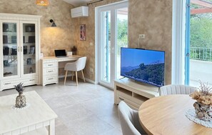 A modern living room with a desk, chair, TV, and a dining area with a table and chairs. - Cozy home in Milohnici with sauna (Milohnici)