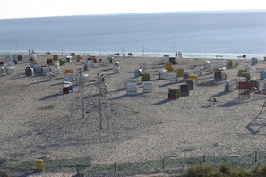 Ein Strand mit zahlreichen bunten Behältern, von denen einige mit Zahlen versehen sind, und ein paar Personen in der Ferne.