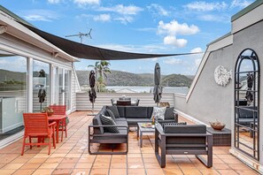 Eine überdachte Terrasse im Freien mit einer Sofagarnitur, Stühlen und einem Tisch.