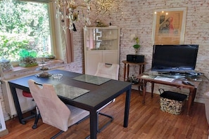 A dining area with a table, chairs, a television, and a cabinet. - Holiday home in KARBY with swimming pool (KARBY)