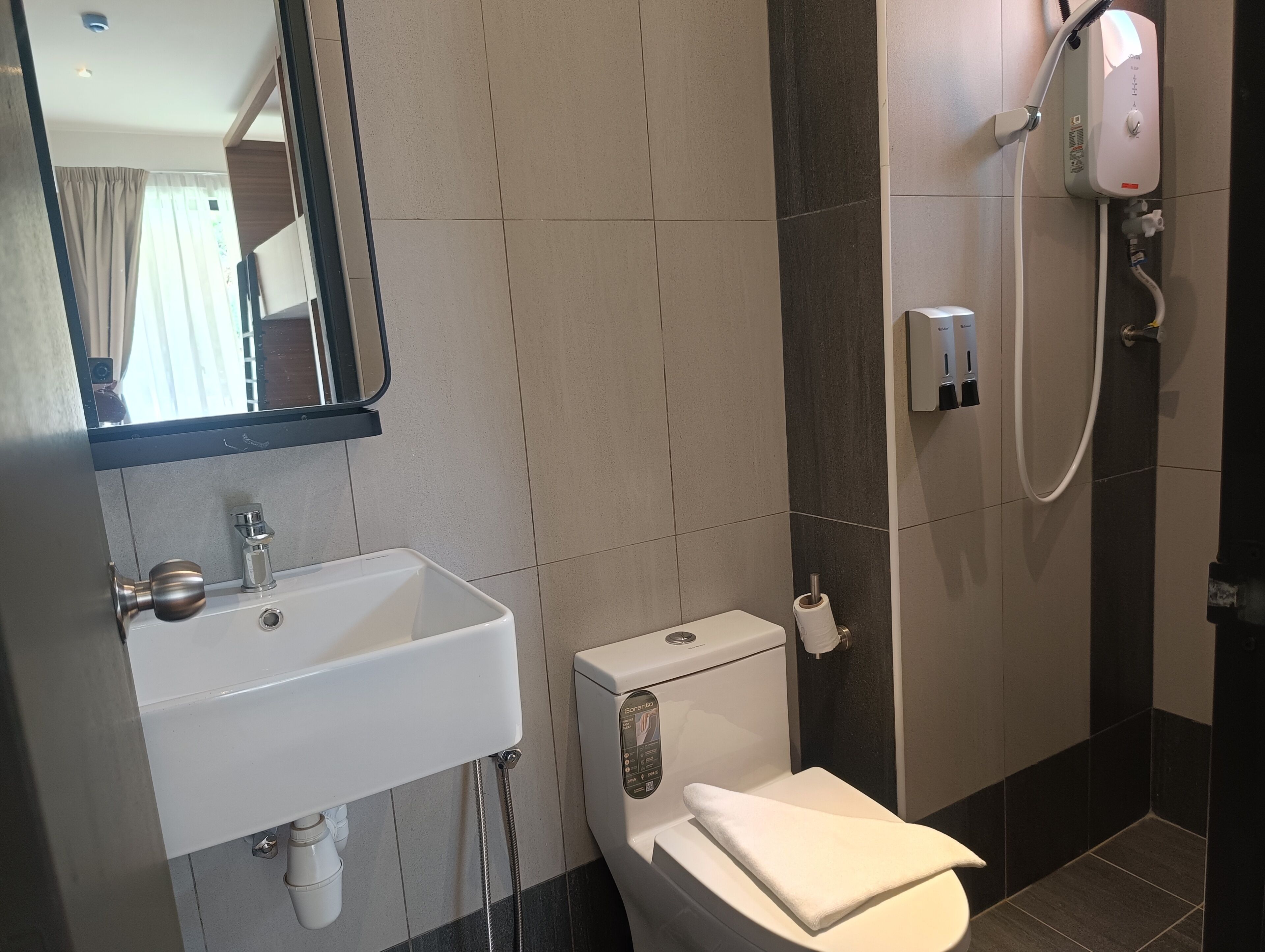 Une salle de bain équipée d’un lavabo, de toilettes et d’une douchette à main.