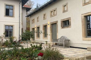 A building with multiple windows, a bench, and a garden area with various plants. - Holiday home with 2 bedrooms (Kurort Gohrisch OT Papstdorf)