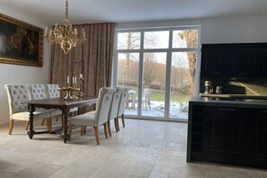A dining area with a chandelier, a large window, and a kitchen with a TV. - Holiday home with 2 bedrooms (Kurort Gohrisch OT Papstdorf)