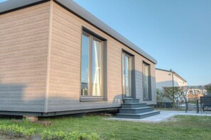 A modern building with large windows, a flat roof, and a small front yard.