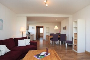 Ein modernes Wohnzimmer mit einem roten Sofa, einem Holztisch und einem Essbereich mit Tisch und Stühlen.