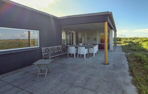 A modern outdoor patio with a table and chairs, a bench, and a view of the landscape. - Luxurious home in Ebeltoft with WiFi (Ebeltoft)