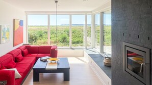 Un salon moderne avec un canapé rouge, une table basse noire et une cheminée.
