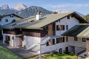 Eine zweistöckige Chalet mit geneigtem Dach, Holzfassade und einer Treppe zu einem Balkon.