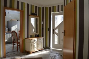 Ein Zimmer mit Holztür, Spiegel, Schrank und Stuhl.