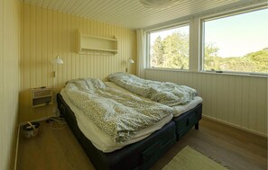 Ein Zimmer mit zwei Betten, einem Fenster, einem Regal und einer Lampe.